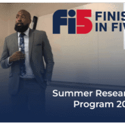 Well dressed student giving speech in front of classroom during Finish In Five's Summer Student Research 2023