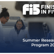 Two female students with lab coats smile together inside of a science lab surrounded by scientific equipment participating in Finish In Five's Summer Student Research 2024